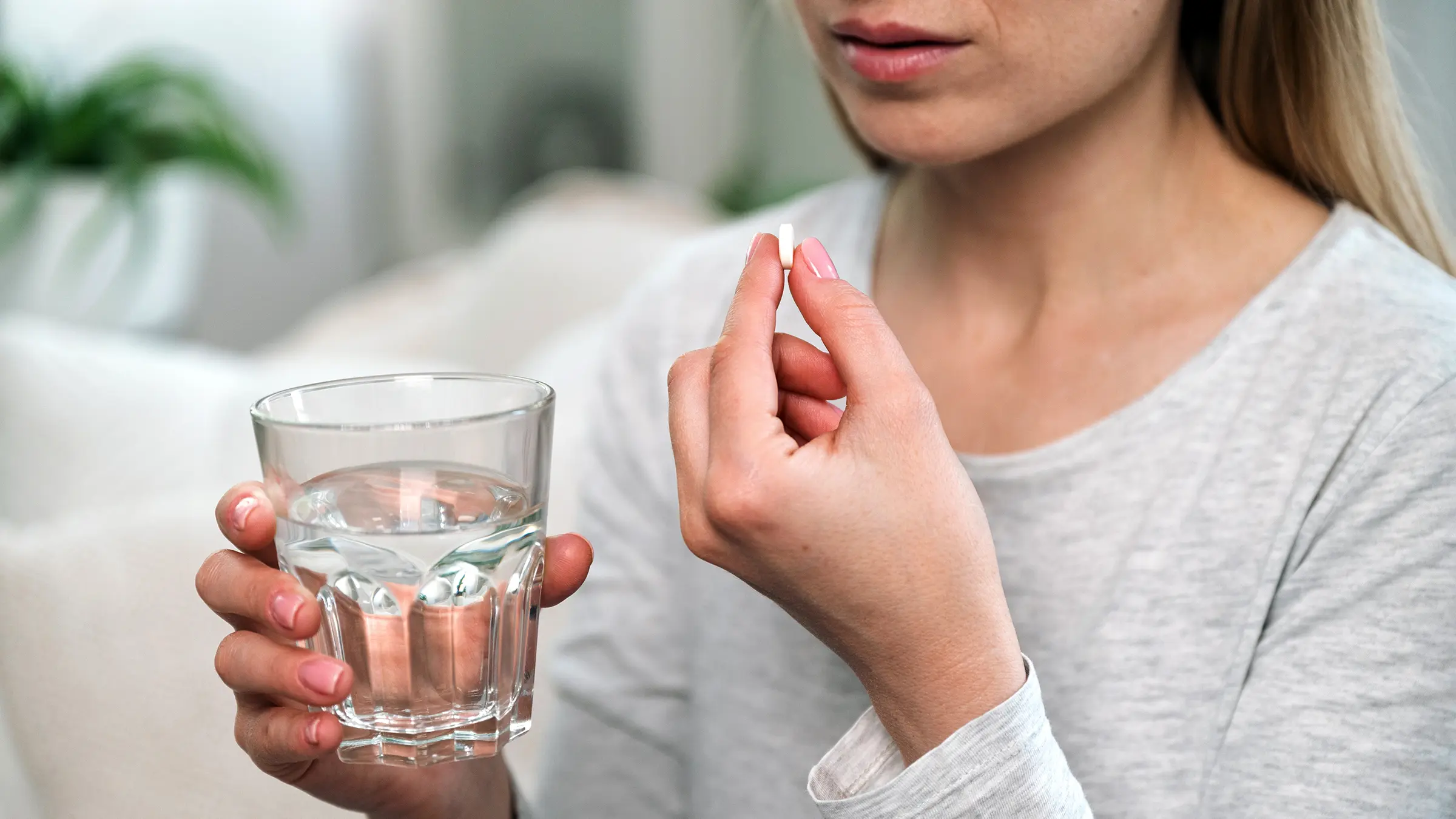 closeup_woman_taking_pill_with_water_1779938807